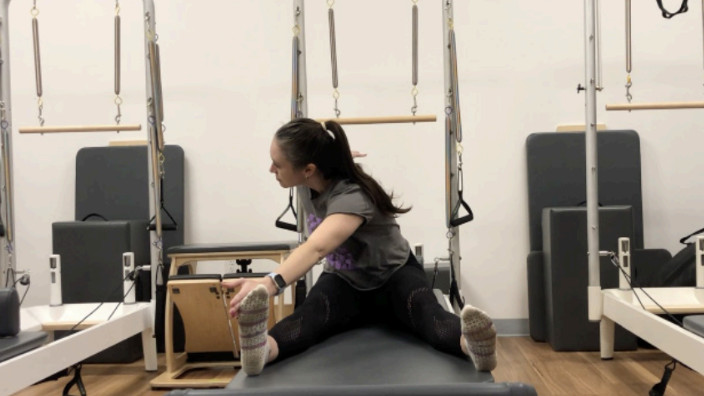 Woman on a Reformer Pilates machine demonstrating an exercise