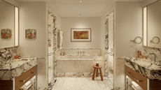 marble bathroom with double vanities, a built-in tub, and marble architraves around the doorways