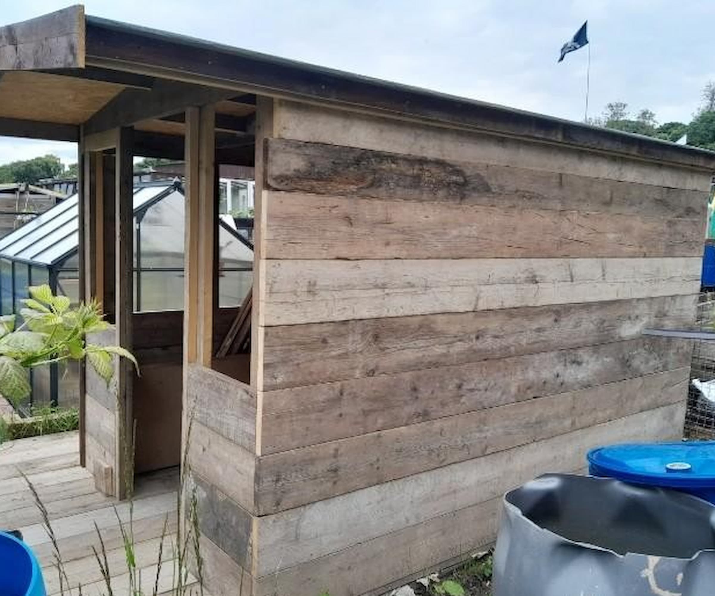 A wooden shed with large wooden overhang and wooden panelled flooring