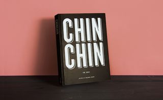 Front cover of the book 'Chin Chin', black background, white lettering, dark wood surface, orange background