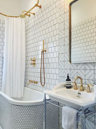 Bathroom with white tiles, gold shower fixtures and fittings, gold mirror and basin