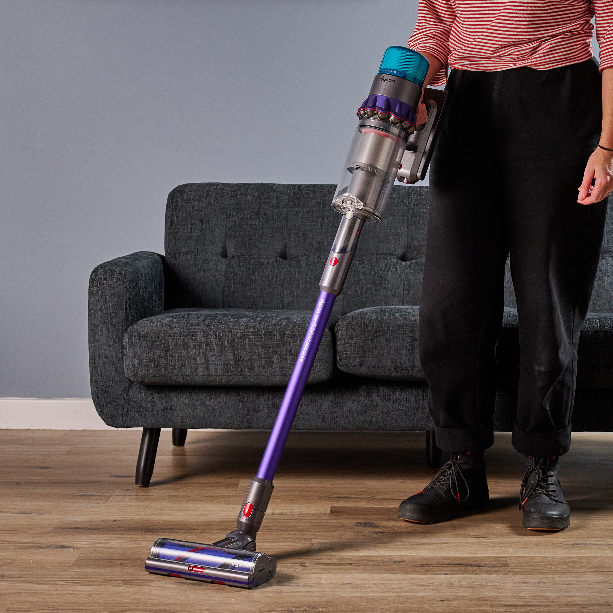 Writer holding Dyson Gen5detect vacuum in front of a sofa