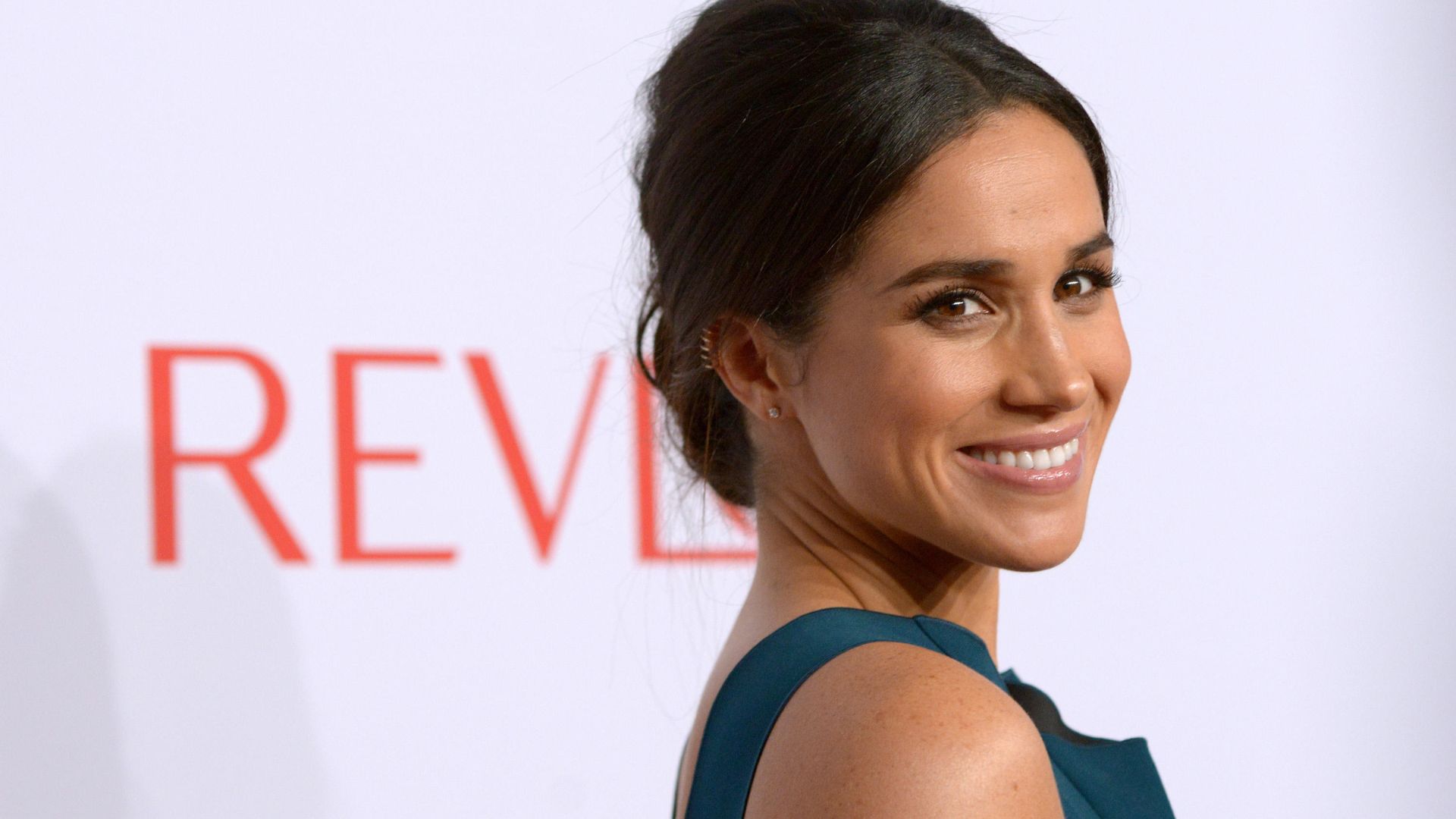 Meghan Sussex looking radiant in front off an advertising sign