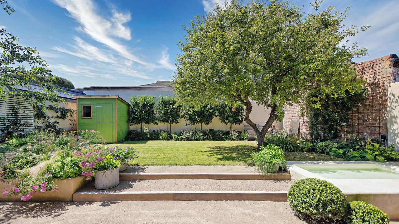 Garden transformation with gravel path pool to the right, a large tree and cute shed at the back 