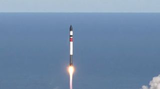 a black, white and red rocket lab rocket launches with the ocean and the sky in the background