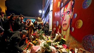 A woman in Brixton leaves flowers beneath a mural of David Bowie, who died at the age of 69 in January