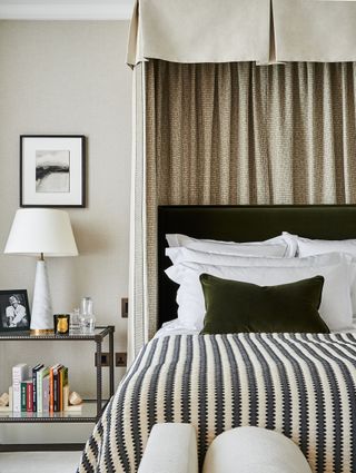 Black and white diamond shaped stripe bedding, green velvet cushion, glass and metal framed bedside table