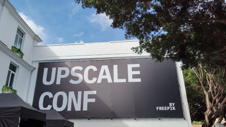 The Freepik Upscale Conf banner on a white building in Malaga