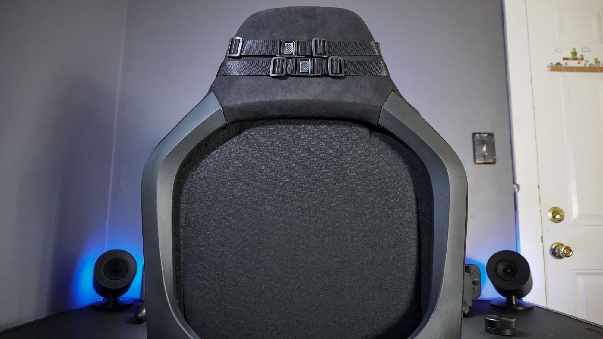 A picture of a gaming chair pushed into a desk with the Razer Clio wireless speaker head cushion attached to its headrest