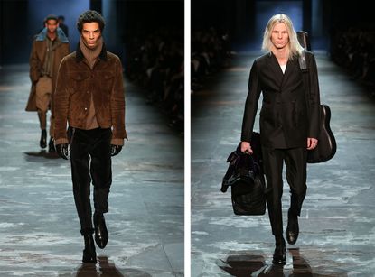 Separate front on view of models on the catwalk, the left in a brown jacket and gloves the right in all black carrying black bags