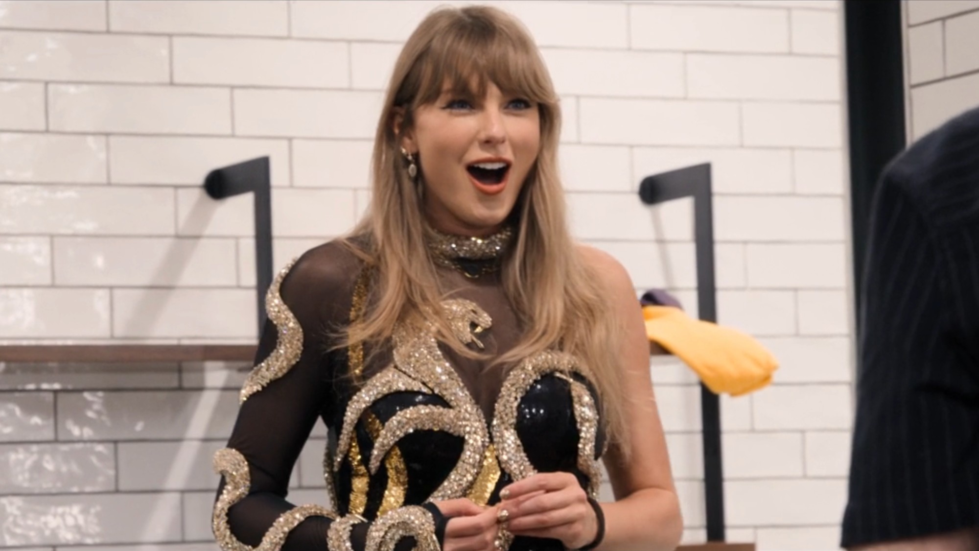Taylor Swift looking shocked while wearing the gold Reputation bodysuit in the End of an Era. 