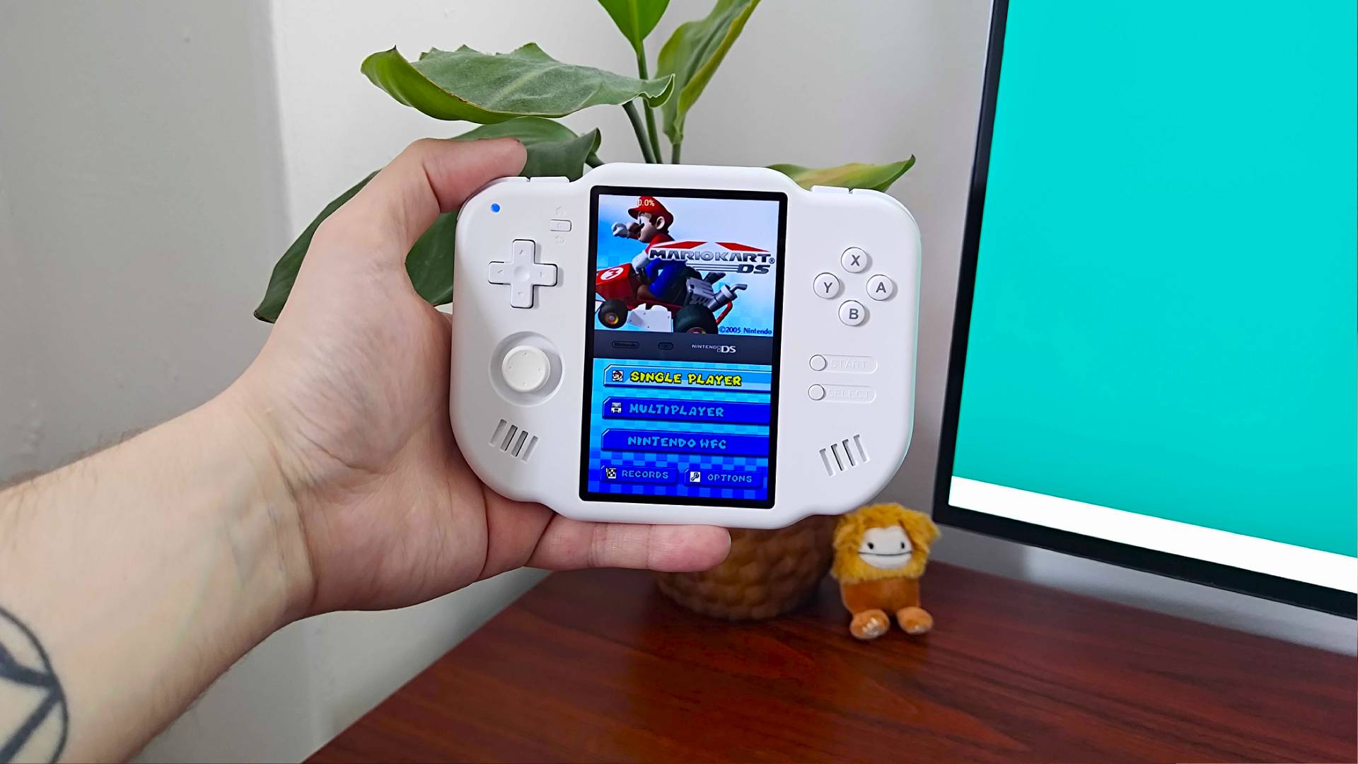 Hand holding MagicX Zero 40 with Mario Kart DS main menu on screen.
