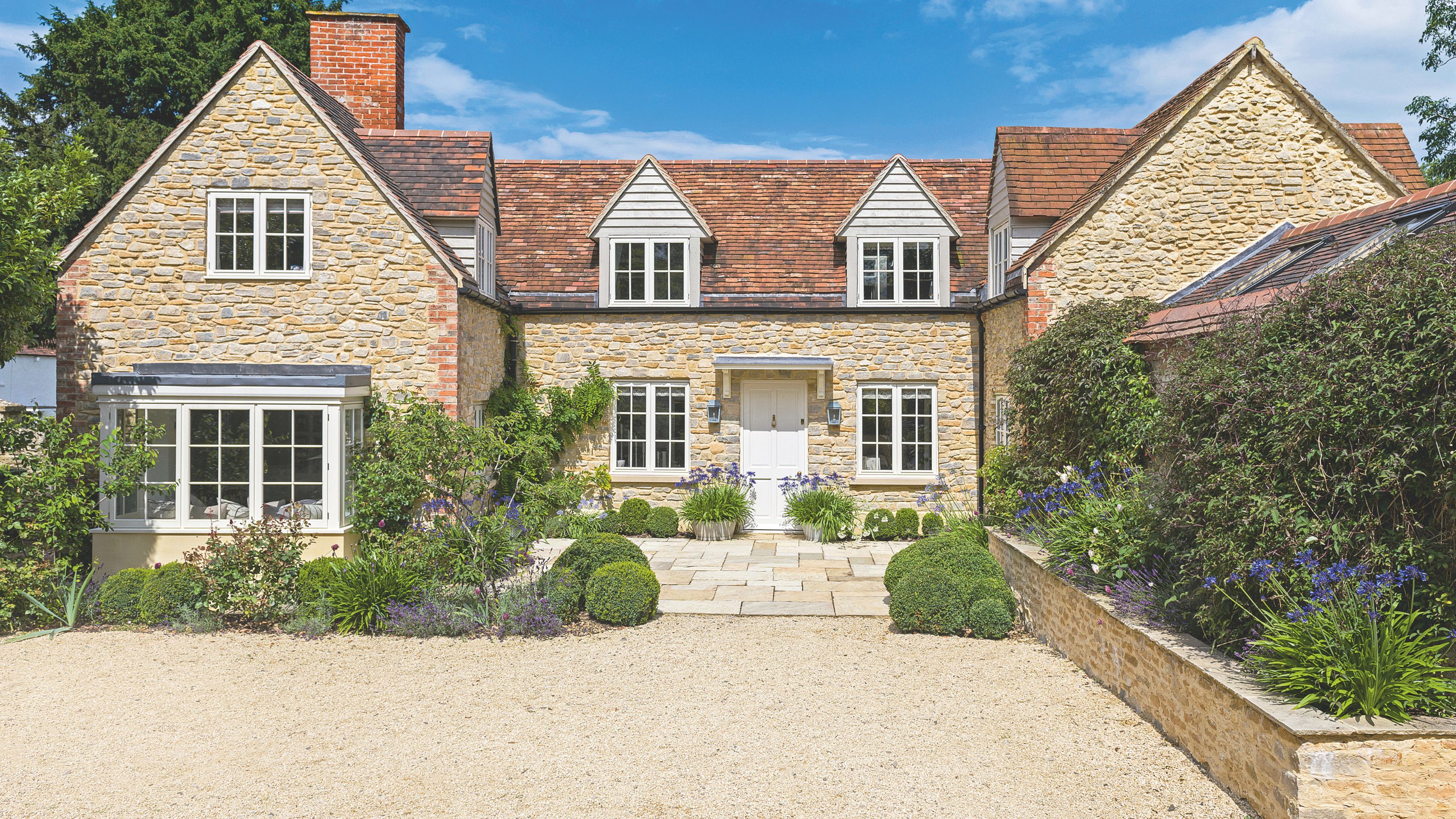 Gravel driveway of stone cottage home with dormer windows