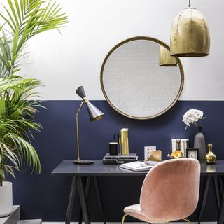 room with round wall mirror statement light and grey desk