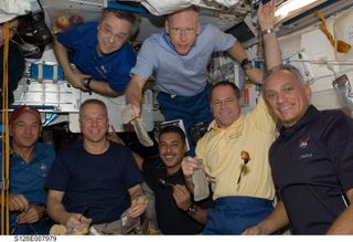 astronauts pose in a cramped room of the international space station