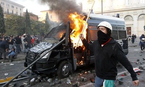 A demonstrator walks past a police car set aflame during an Occupy Wall Street-inspired protest in Rome Saturday.