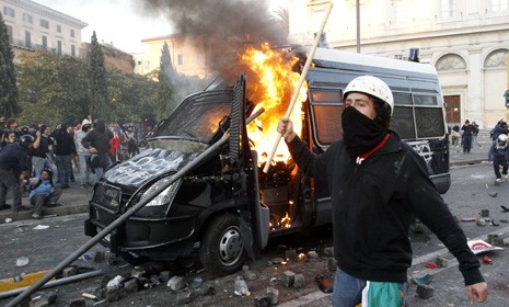 A demonstrator walks past a police car set aflame during an Occupy Wall Street-inspired protest in Rome Saturday.