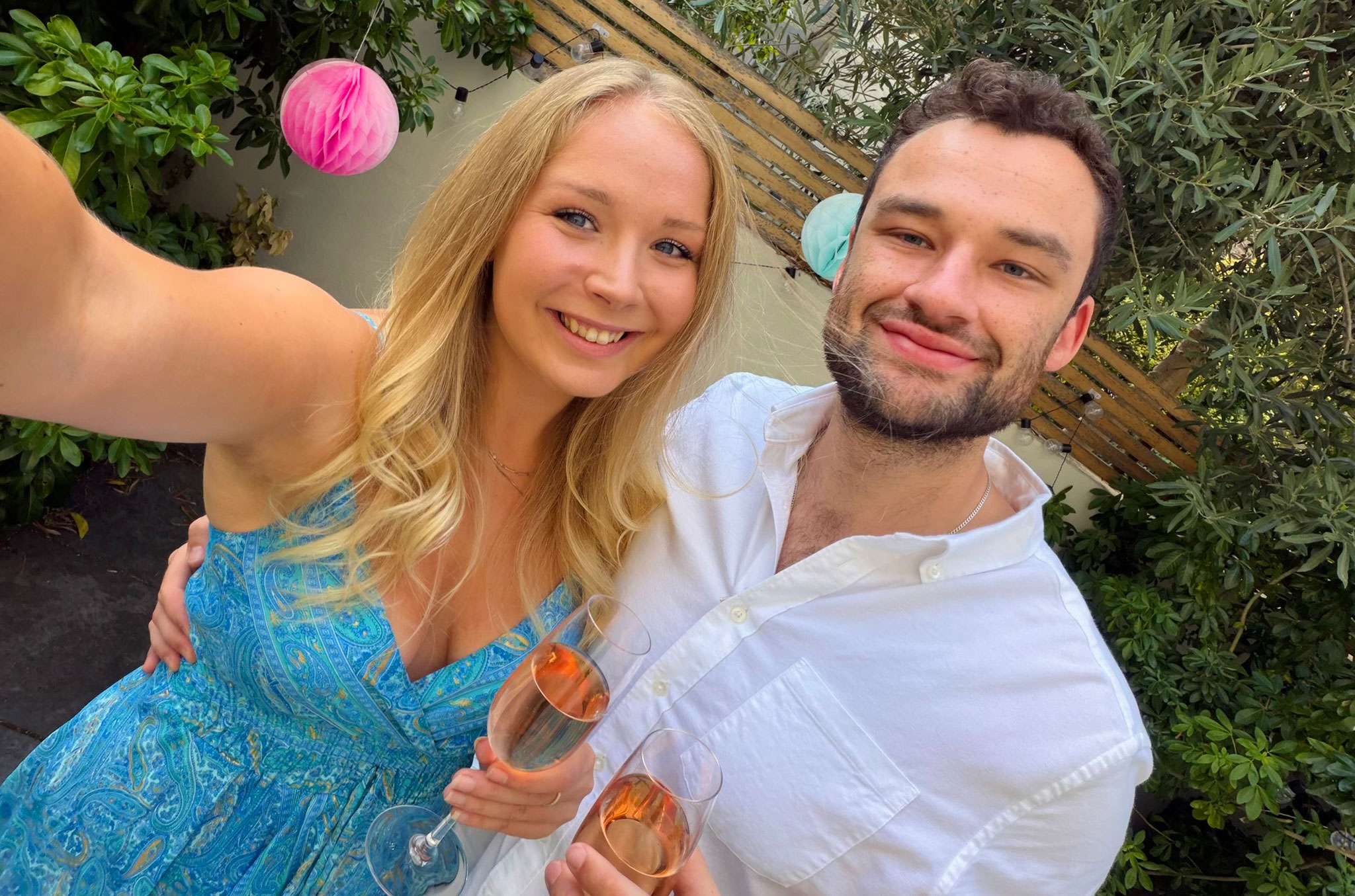 Anabel Riley and partner in the garden holding glasses of ros&eacute; sparkling wine