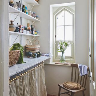 Small pantry with marble shelf and brass rail with under-counter curtain with striped ticking fabric