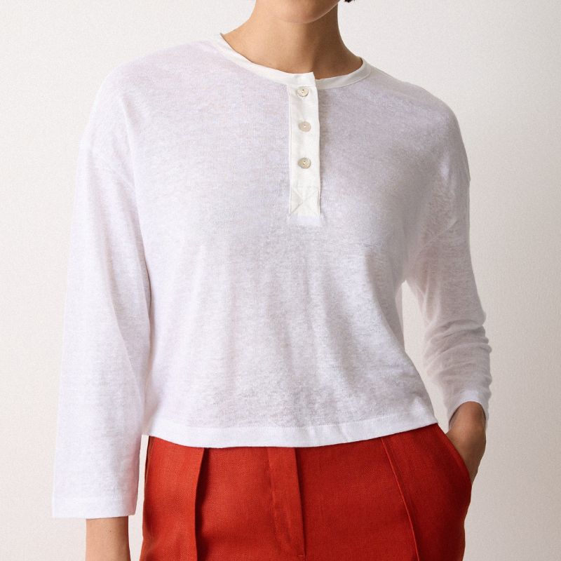 A model wears a white linen top by Jigsaw with red trousers