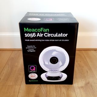 The MeacoFan 1056 Air Circulator packaged in a black box and sat on a wooden floor