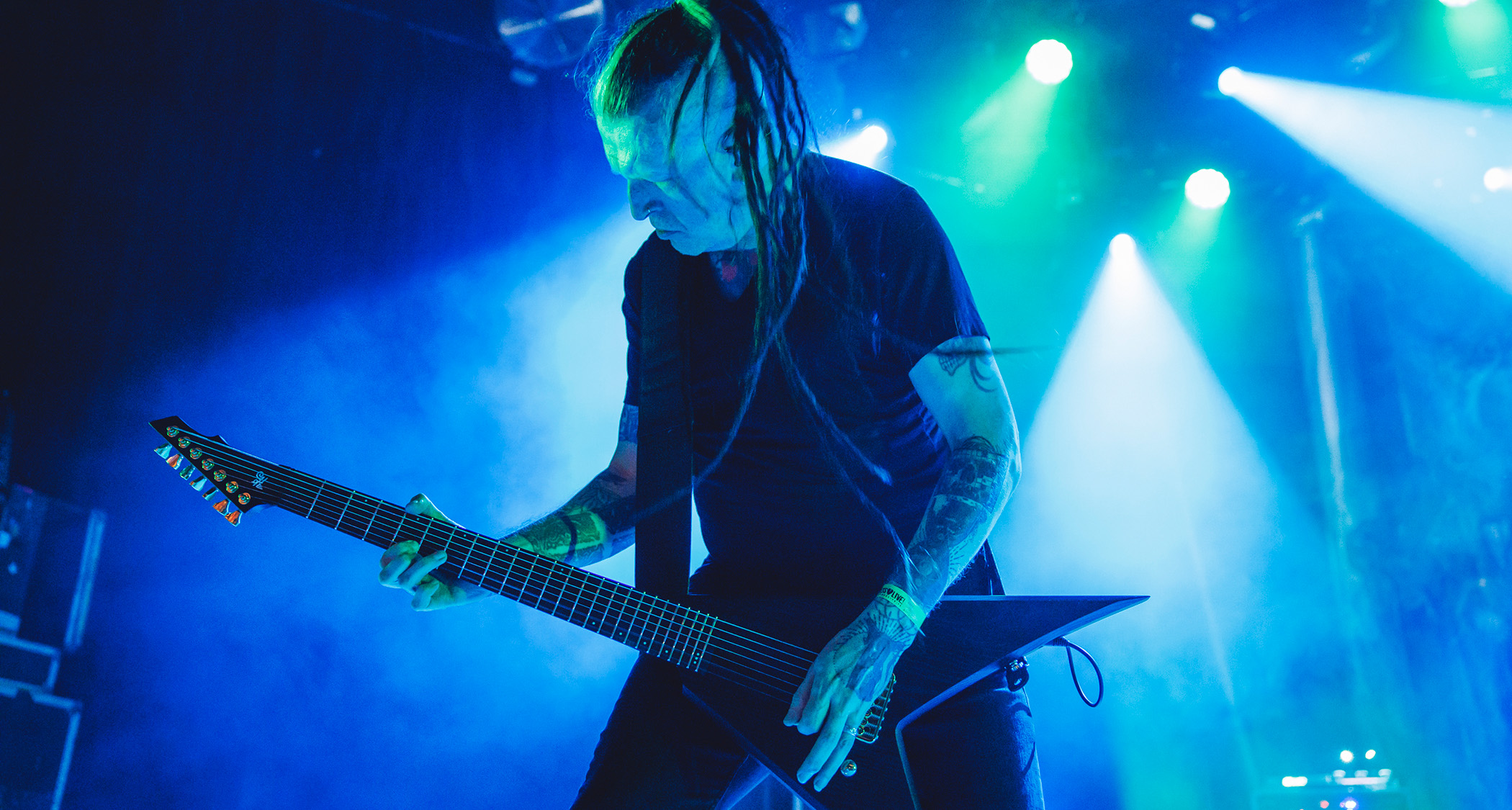 On a stage light in blue and green, a dreadlocked Greg Mackintosh of Paradise Lost plays his 7-string V.