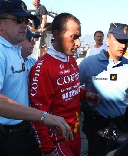 Gendarmes escort Cristian Moreni through the gathered media