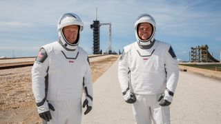 Astronauts Doug Hurley (left) and Bob Behnken in their SpaceX spacesuits at Launch Pad 39A with their Falcon 9 rocket and Crew Dragon spacecraft in the background before launch. The SpaceX pressure suits are designed to keep astronauts safe in the spacecraft and not for spacewalks.