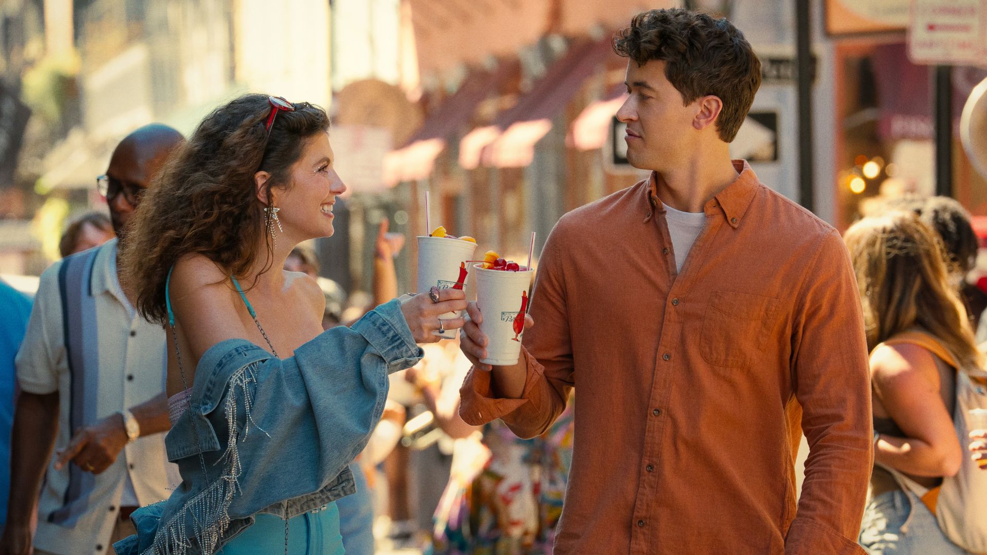Poppy and Alex walk through a crowded New Orleans street