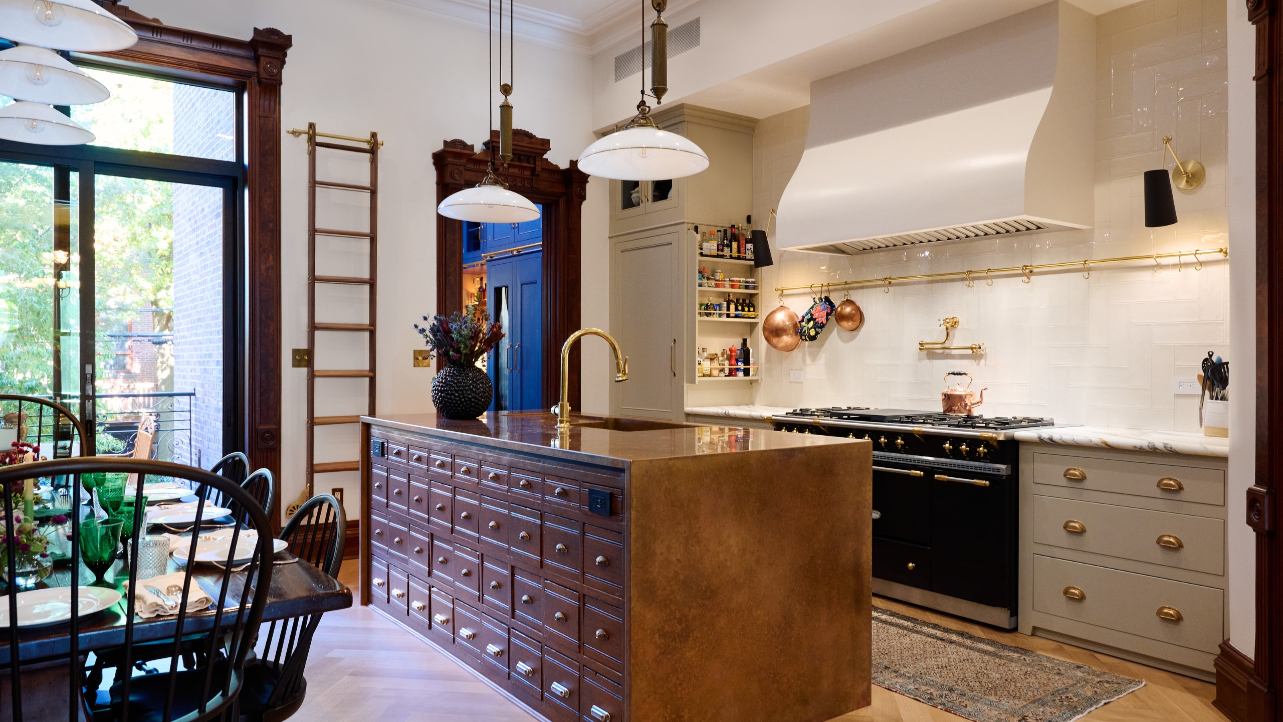 A New York home's kitchen with mushroom color cabinets, a wood island, and marble countertops