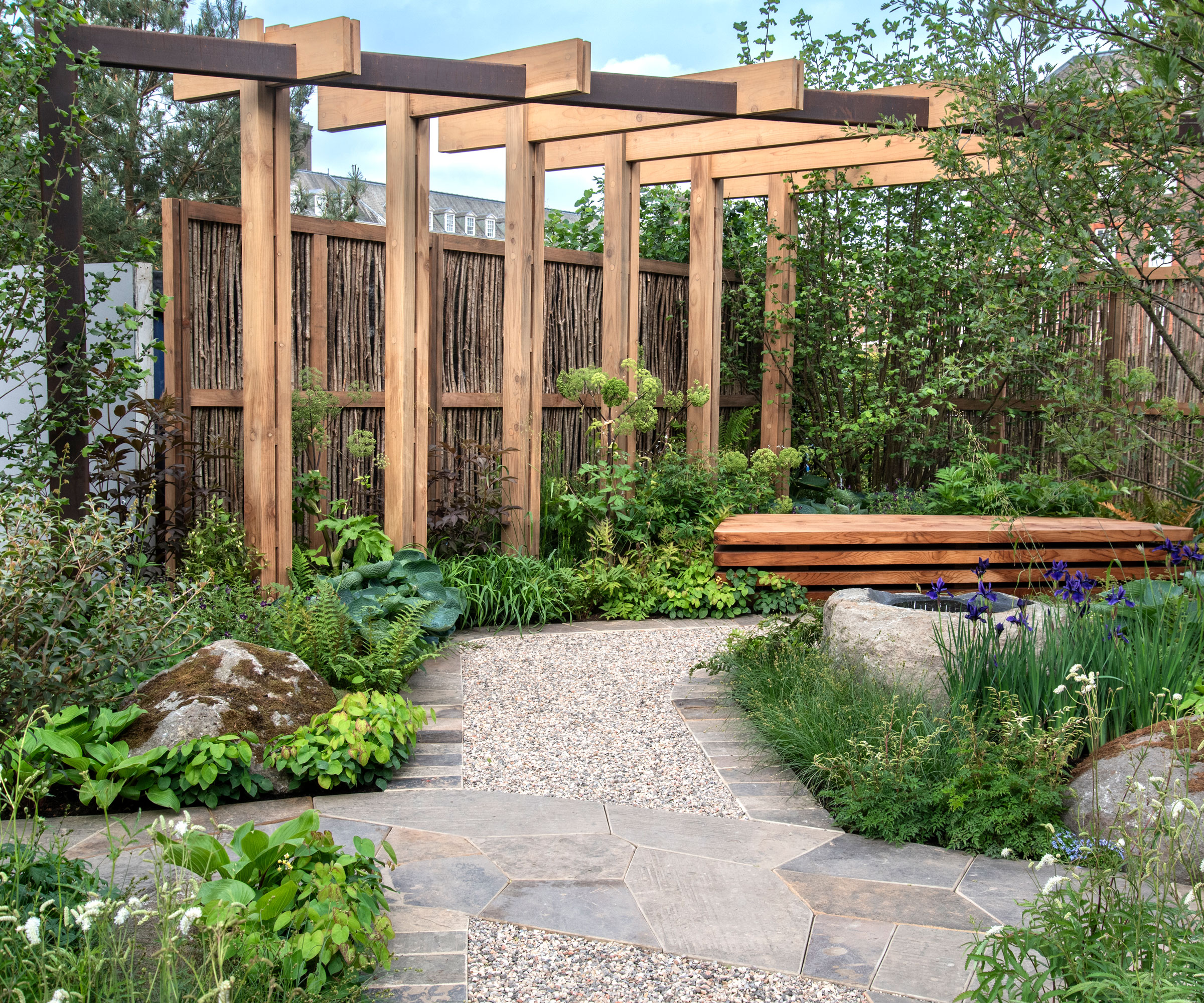 modern garden design with large wooden pergola, garden bench, planting and landscaping with rocks and gravel