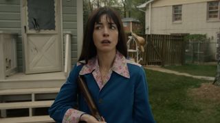 Anne Hathaway looking terrified with a rifle in The End of Oak Street.