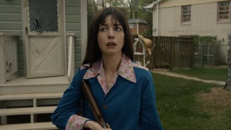 Anne Hathaway looking terrified with a rifle in The End of Oak Street.