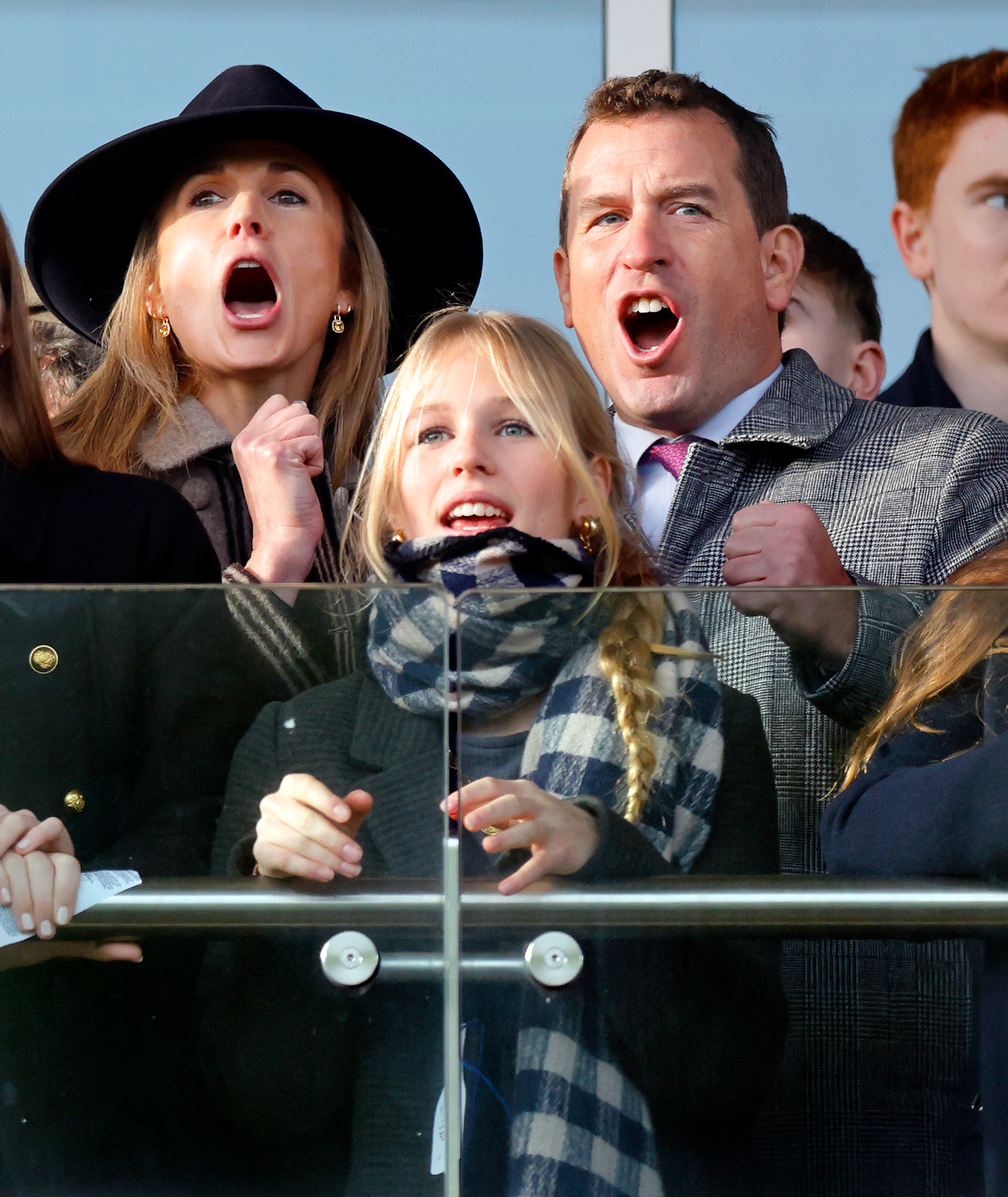 Harriet Sperling, Peter Phillips and Isla Phillips cheering at a horse race