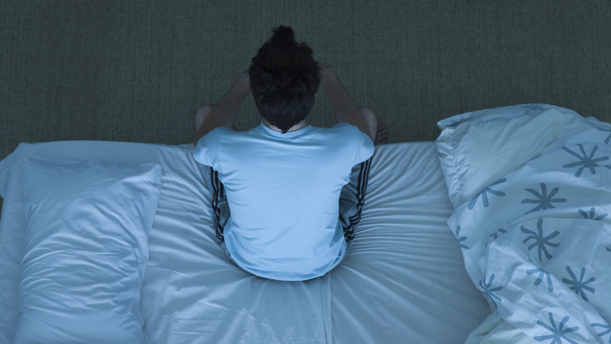 Как лучше спать: мужчина сидит на краю кровати, потому что у него слишком много стресса, чтобы спать
