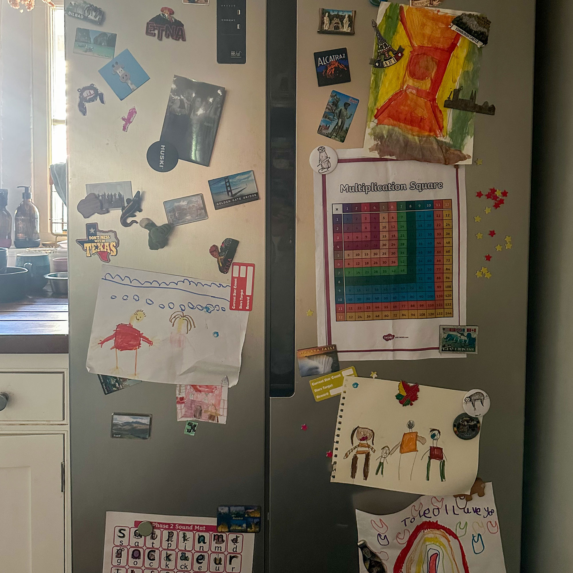 Stainless steel double fridge covered in magnets and childrens' artwork