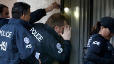 Immigration and Customs Enforcement (ICE) agents from the Department of Homeland Security look into the window of an apartment while executing search warrants in 2015.