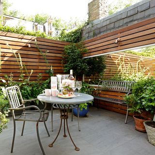 urban garden with wooden wall and wine glasses in table and chair
