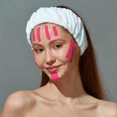 a woman with pink face tape on her face