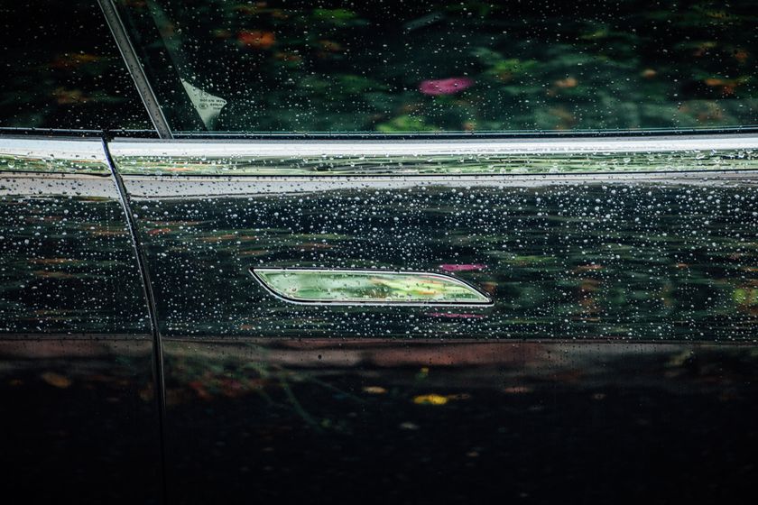A Tesla door handle on a Model S with drops of rain on the door