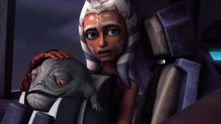 Still from the T.V. show Star Wars: The Clone Wars. Inside a spaceship's cockpit we see Ahsoka (orange face with white markings and blue and white stripped head tails) sitting down with Rotta the Huttlet on her lap (a small, yet rotund slug-like creature with big yellow eyes).