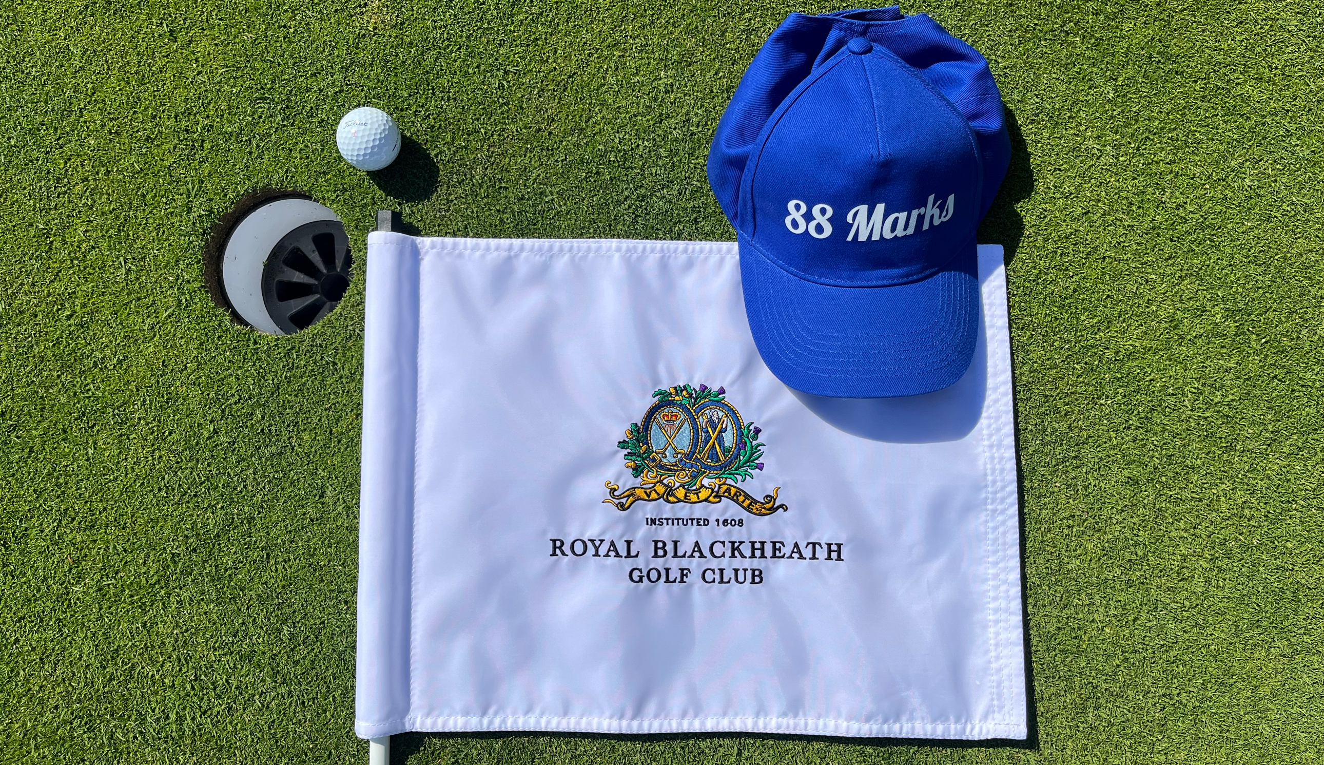 A flag, hat and golf ball near a hole
