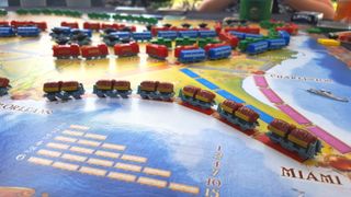 best board games for two – part of a Ticket to Ride board, several train car miniatures tanding in a row on top
