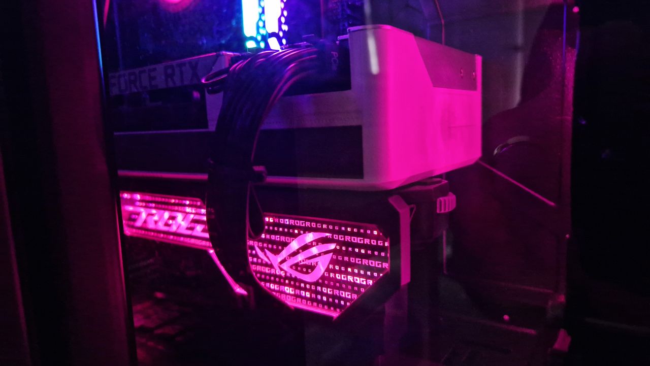 The Asus ROG Herculx GPU support bracket propping up an RTX 3090 with its lights shining pink