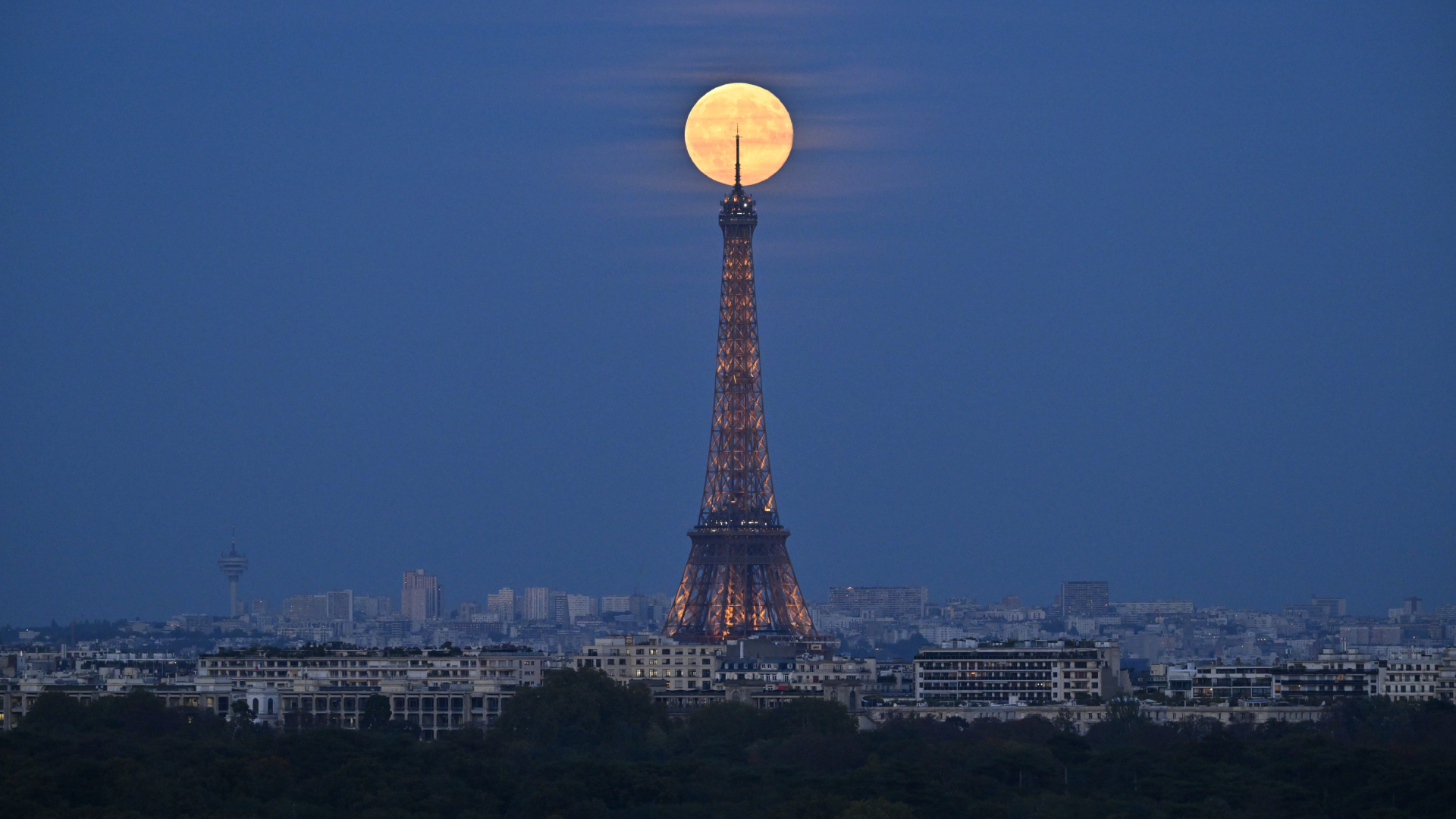  A bright full moon shines just behind the top of the Eiffel Tower in Paris.