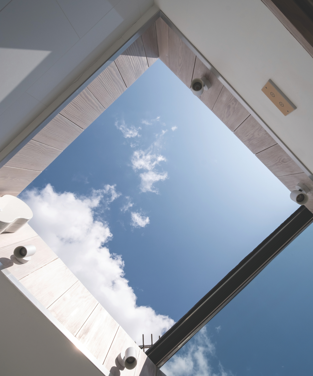 Open roof from below looking up onto blue, cloudy sky