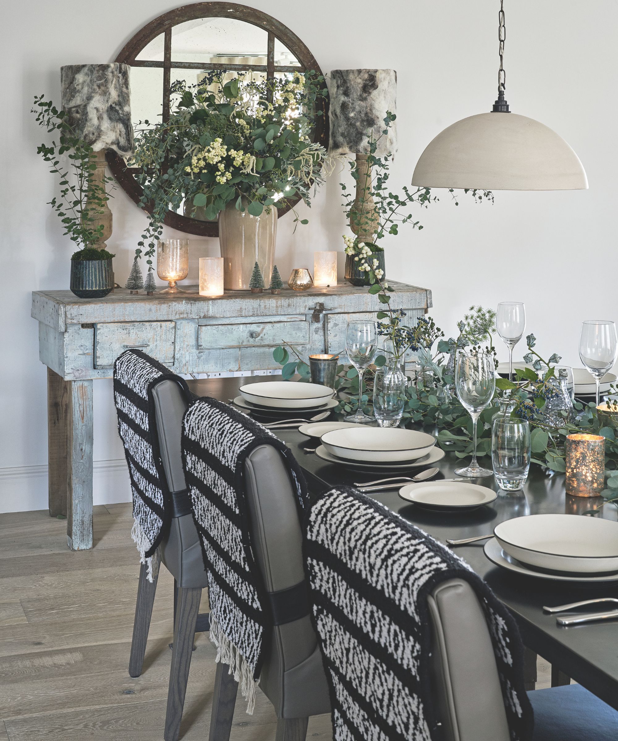 Black tale with white crockery, gray chairs, and a eucalyptus centerpiece