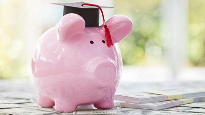 Piggy bank wearing graduation cap sitting on money