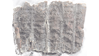 An unrolled curse tablet with transcription of the text overlaid in black cursive handwriting.