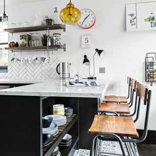 white kitchen with black island and wood bar stools with open shelving